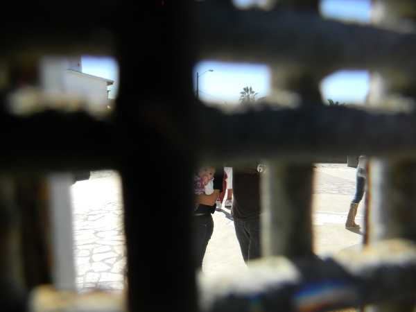 Una madre en Tijuana no se ve completamente a través de la pared del Parque de la Amistad. Este parque es un lugar de encuentro de los deportados con sus familias en San Diego. Foto de Joel Ramos. 